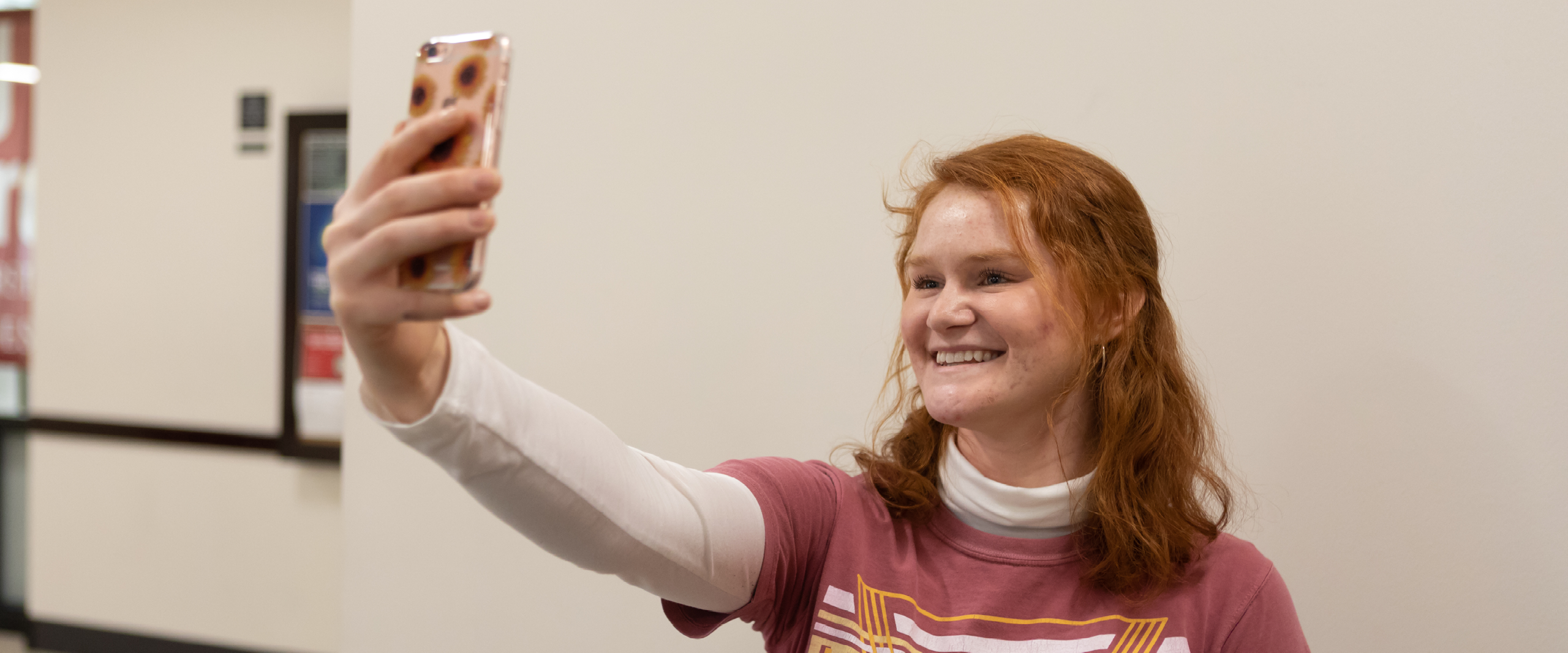 Student taking a selfie in front of a plain white background